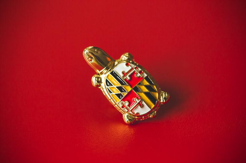 President Darryll J. Pines turtle pin with the Maryland state flag shell design against a red backdrop.