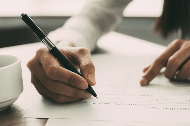 student hands holding pen over form paper