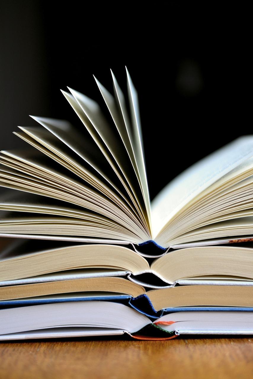 Photo of a stack of four open books on a wooden table