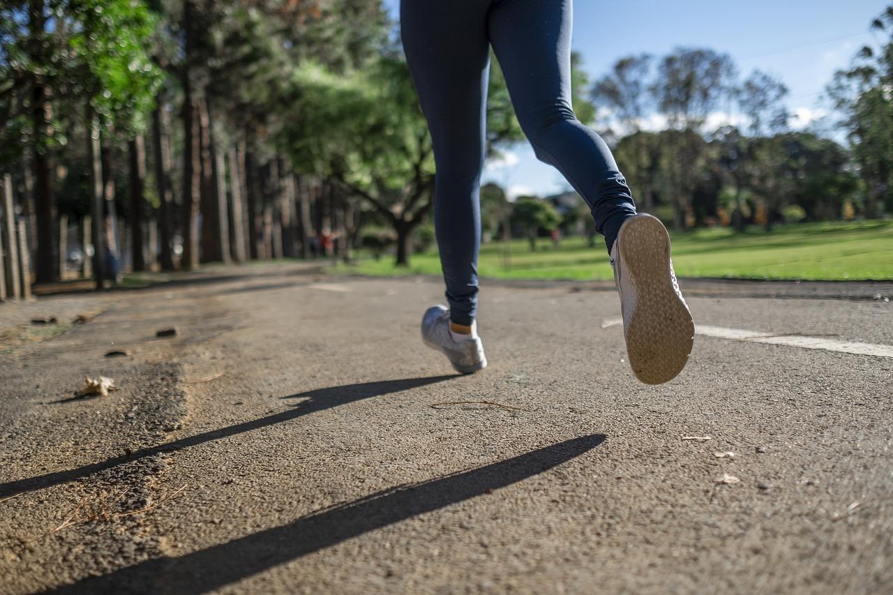 Photo of person's legs and feet while running on asphalt