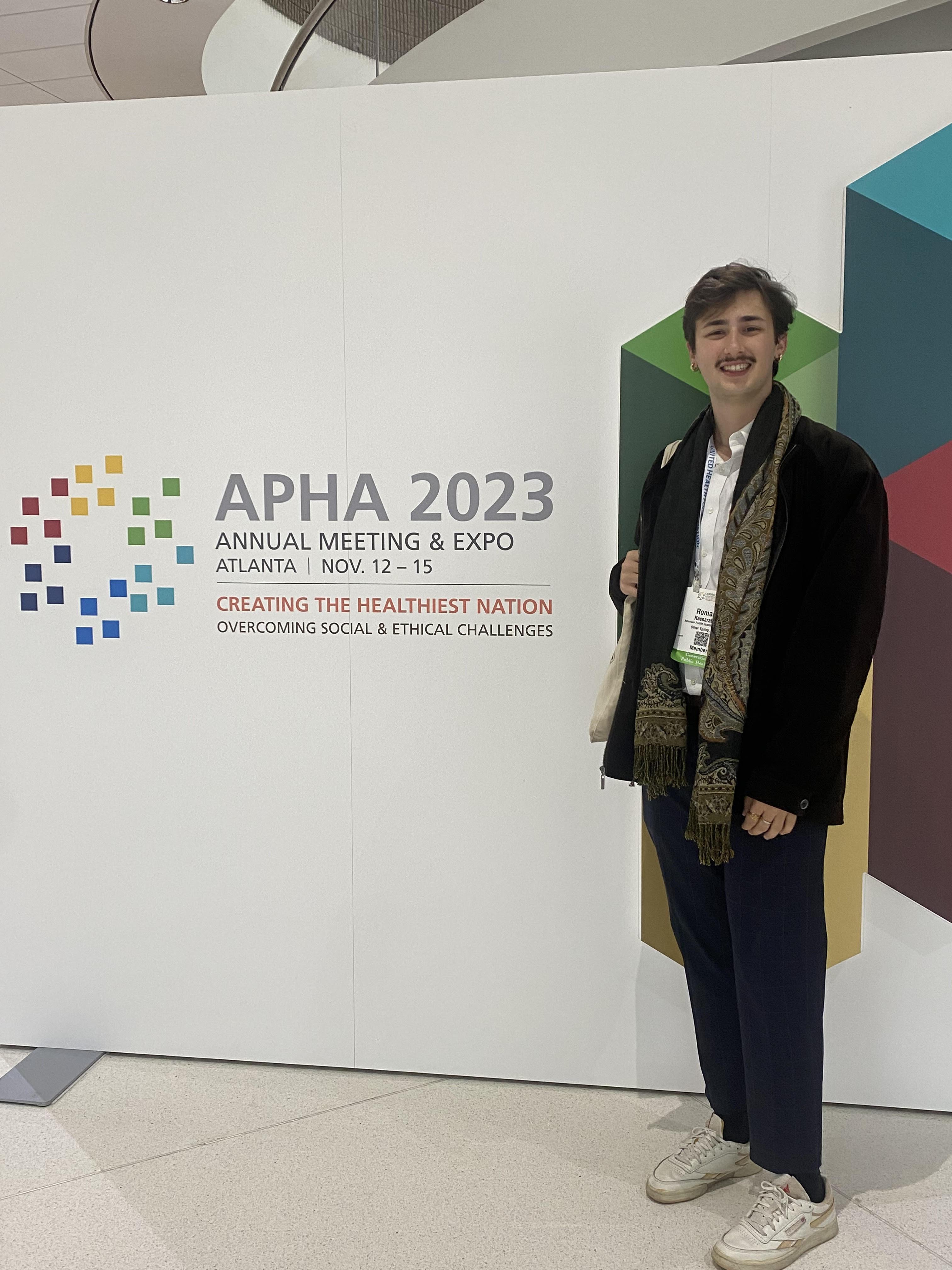 Roman Kassaraba standing in front of APHA Conference backdrop