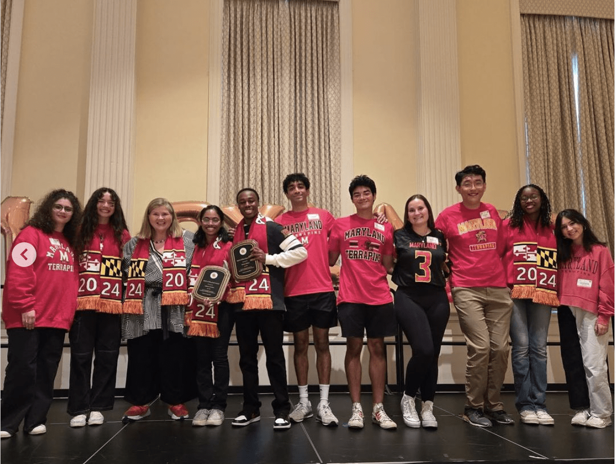 Eleven UMD students wearing red and black clothes on a stage