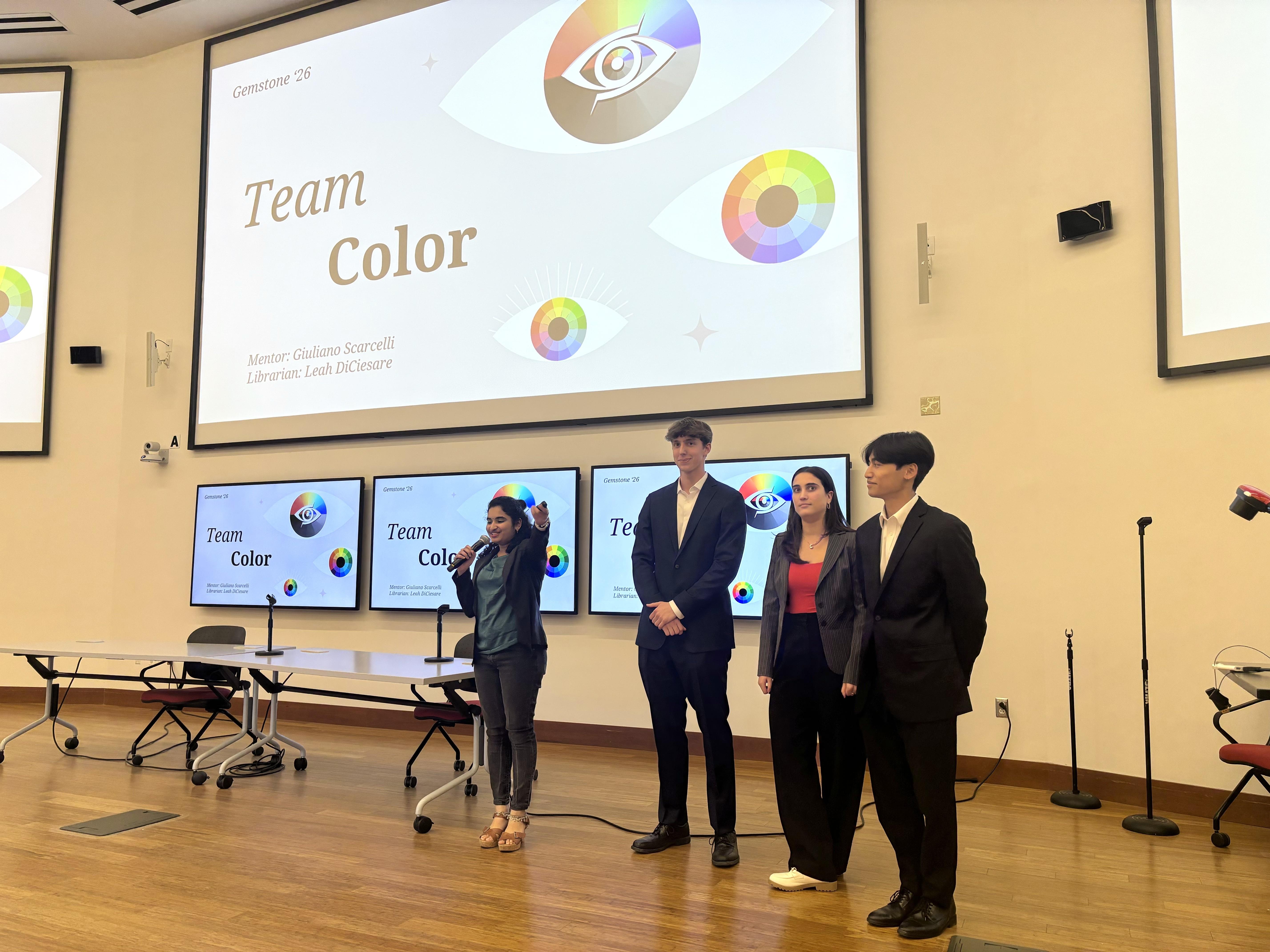 Four students of Team Color standing in front of a presentation in a lecture hall.