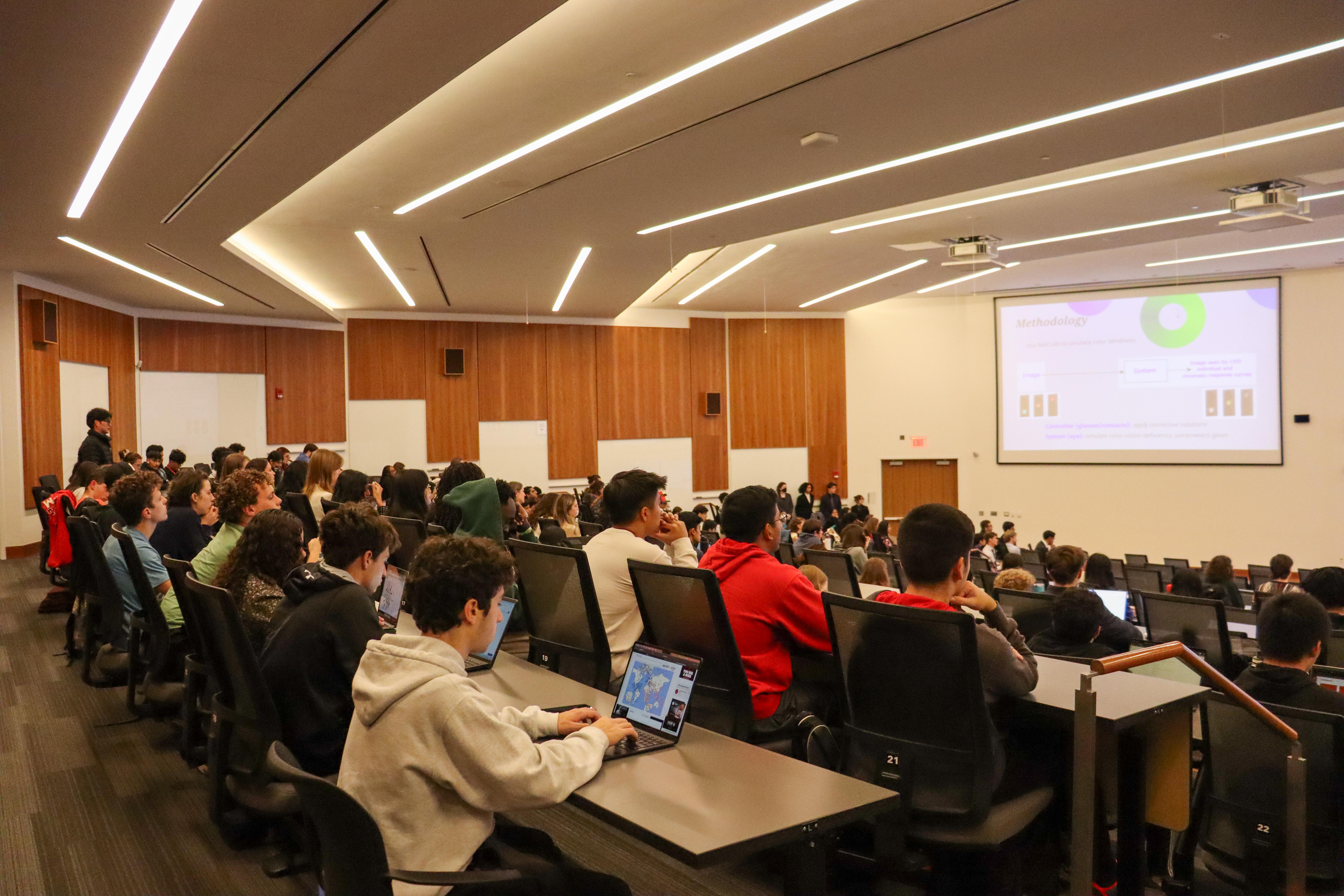 Photo of students in lecture hall looking at presentation slide