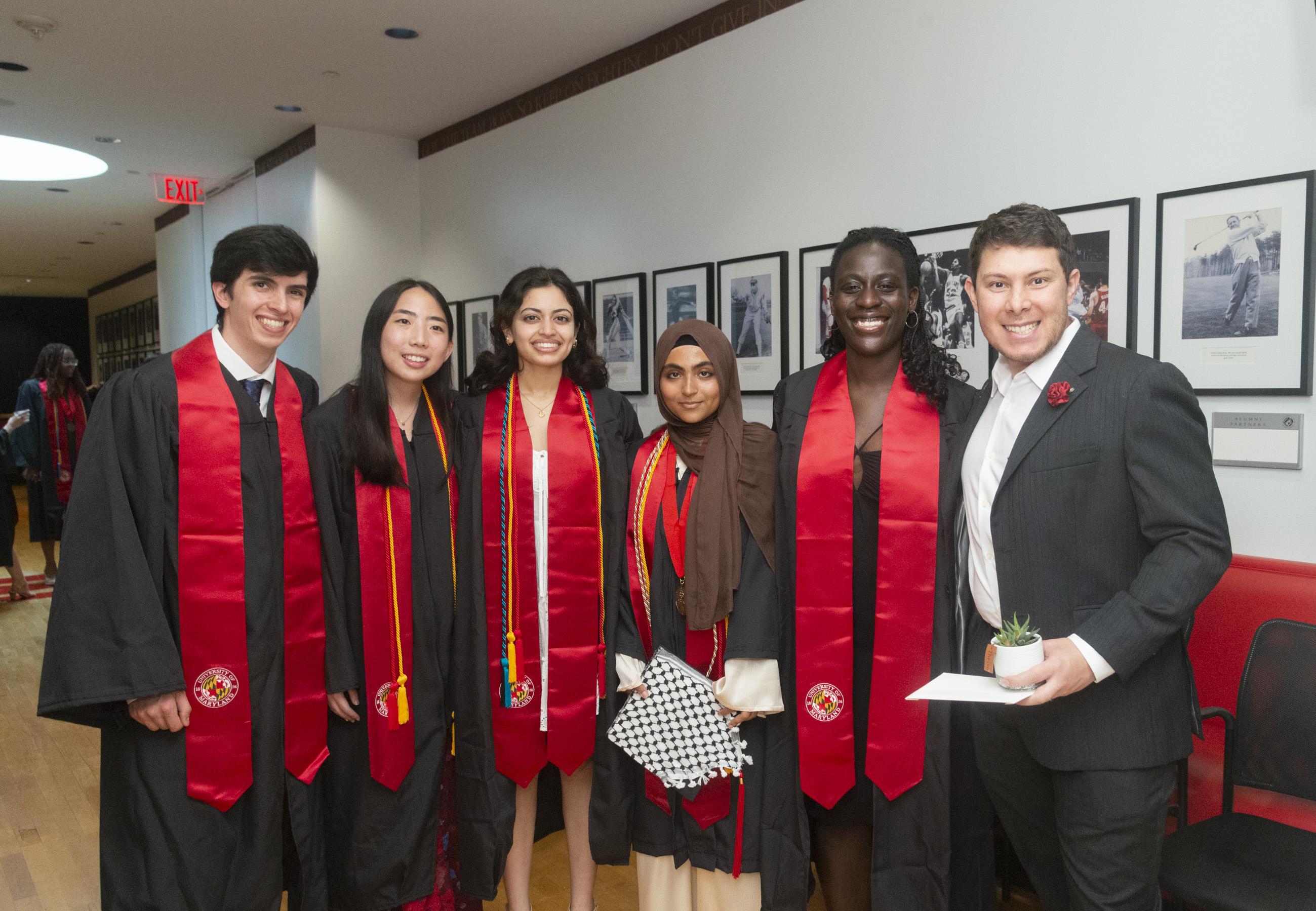 Six students wearing black graduation gowns and red stoles 