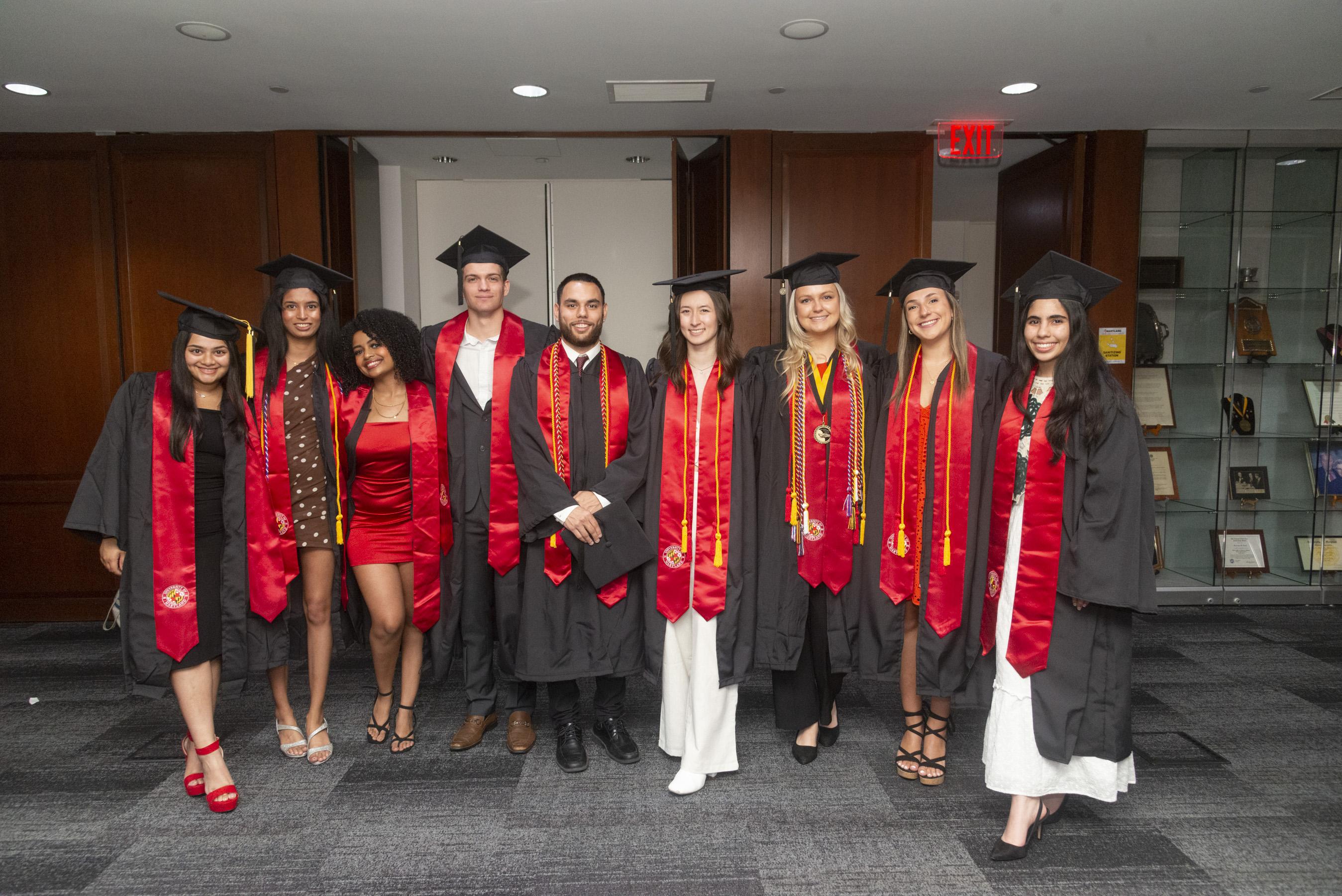 Group of graduating Gemstone students posing for photo in black and red gowns