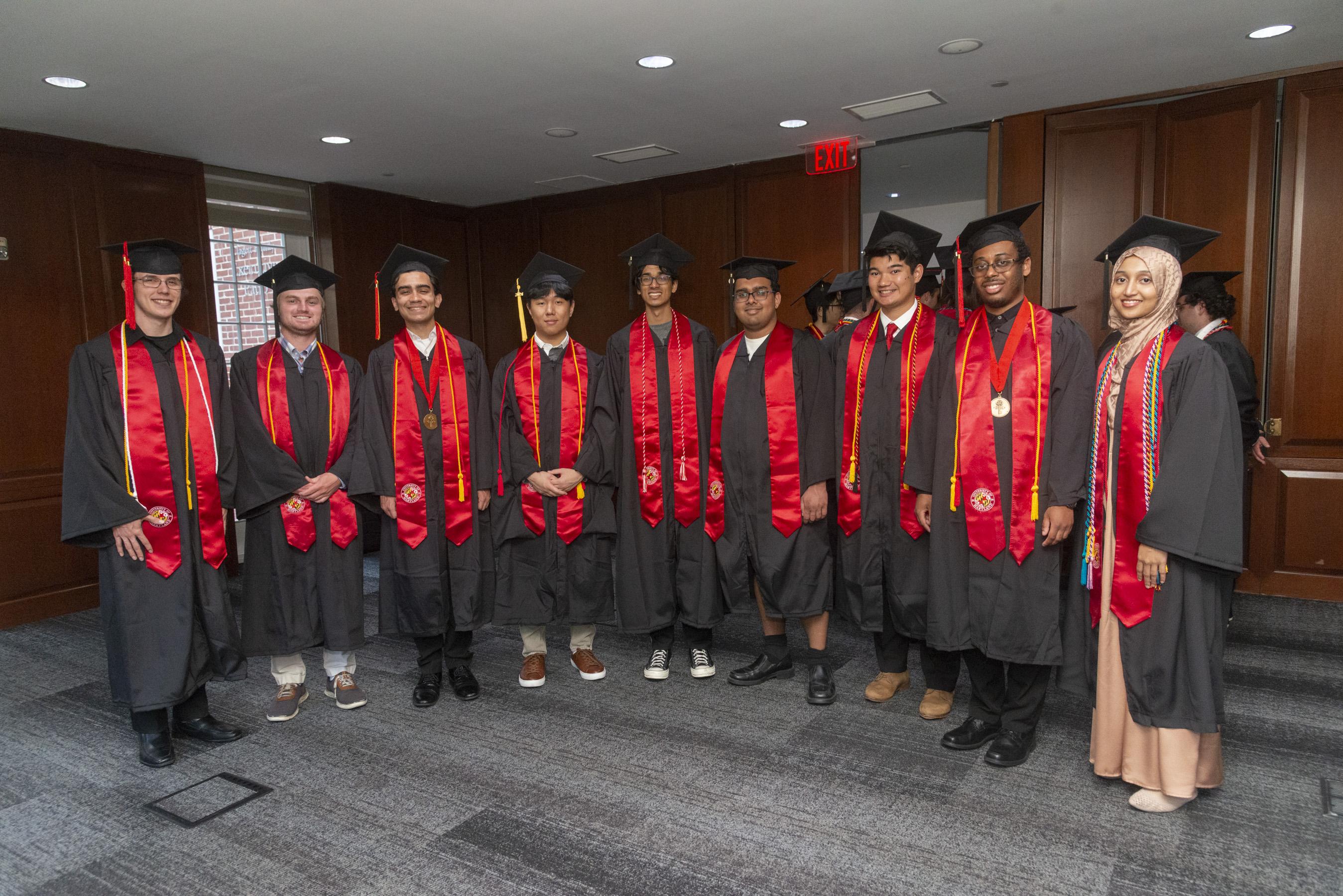 Group of graduating Gemstone students posing for photo in black and red gowns