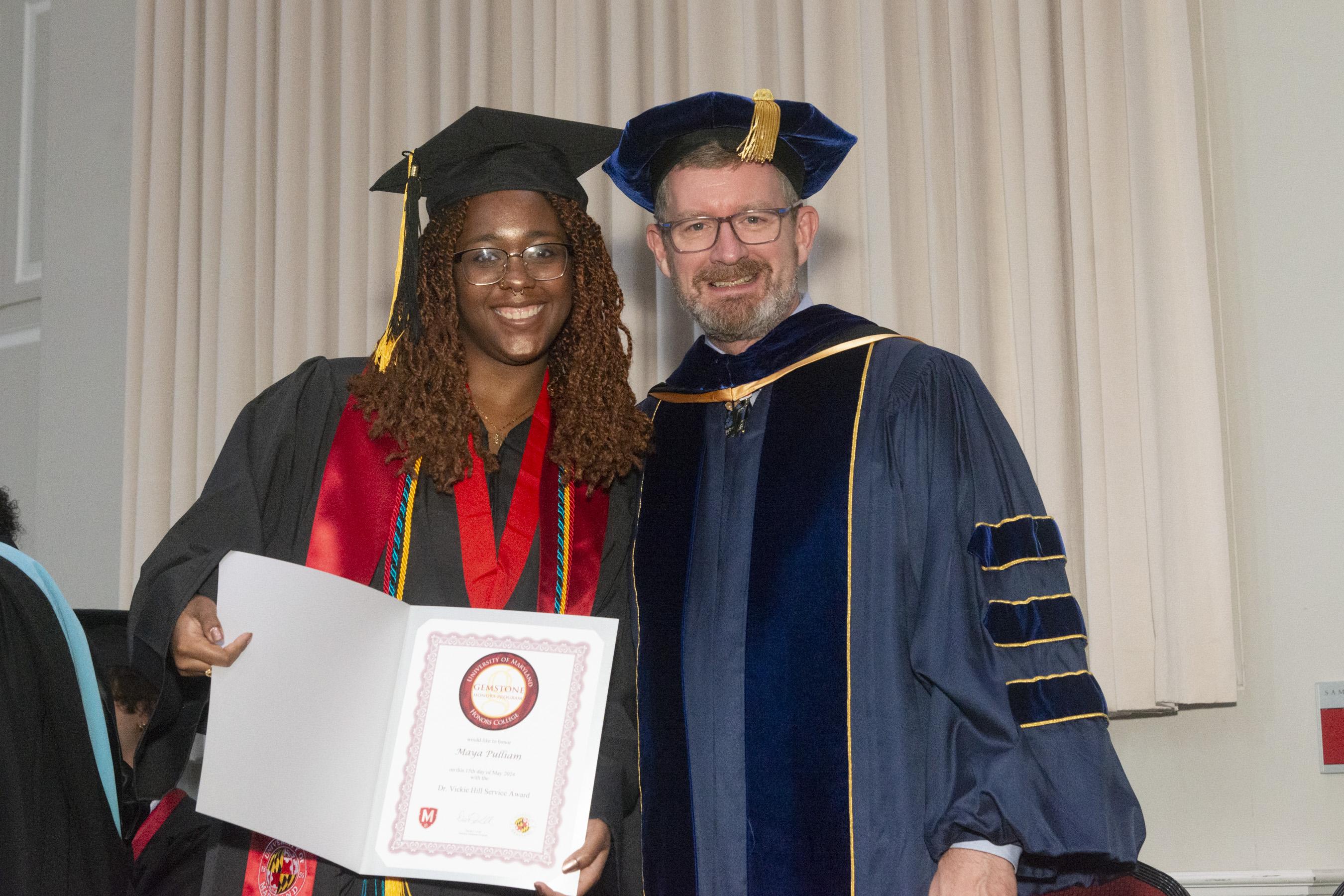 Gemstone director posing with student receiving their award