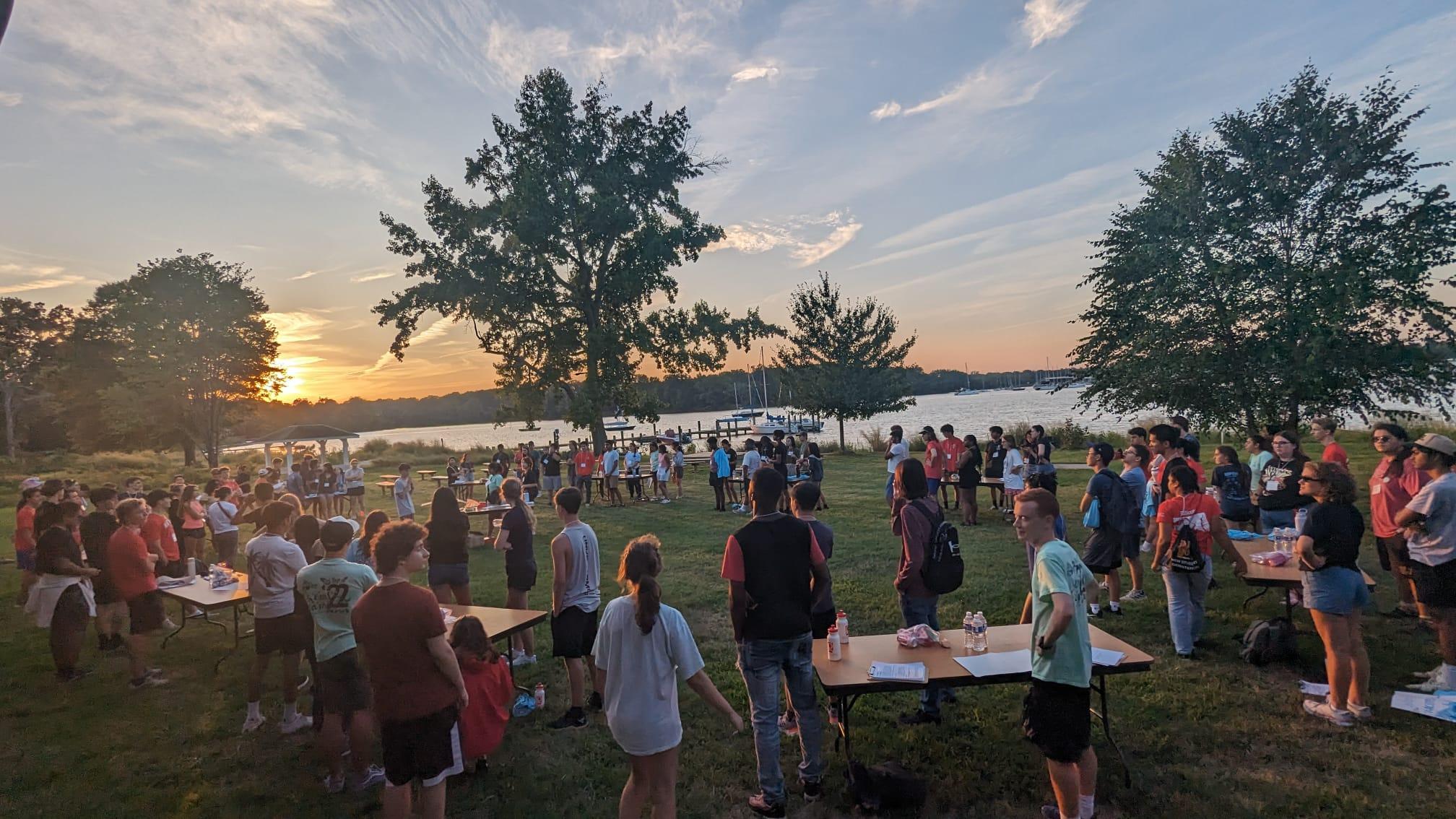 Group of students gathered on lawn in front of lake