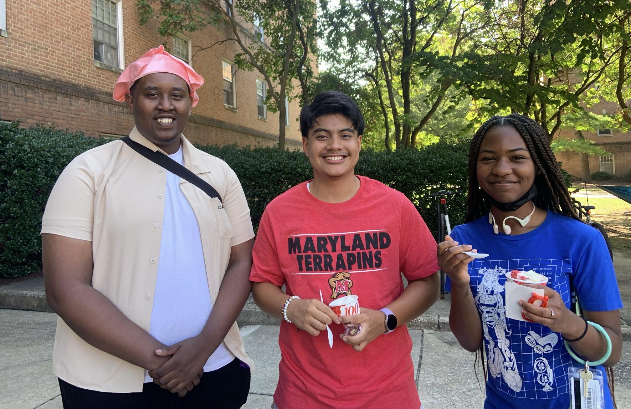 Three students smiling for photo, two are holding ice cream cups