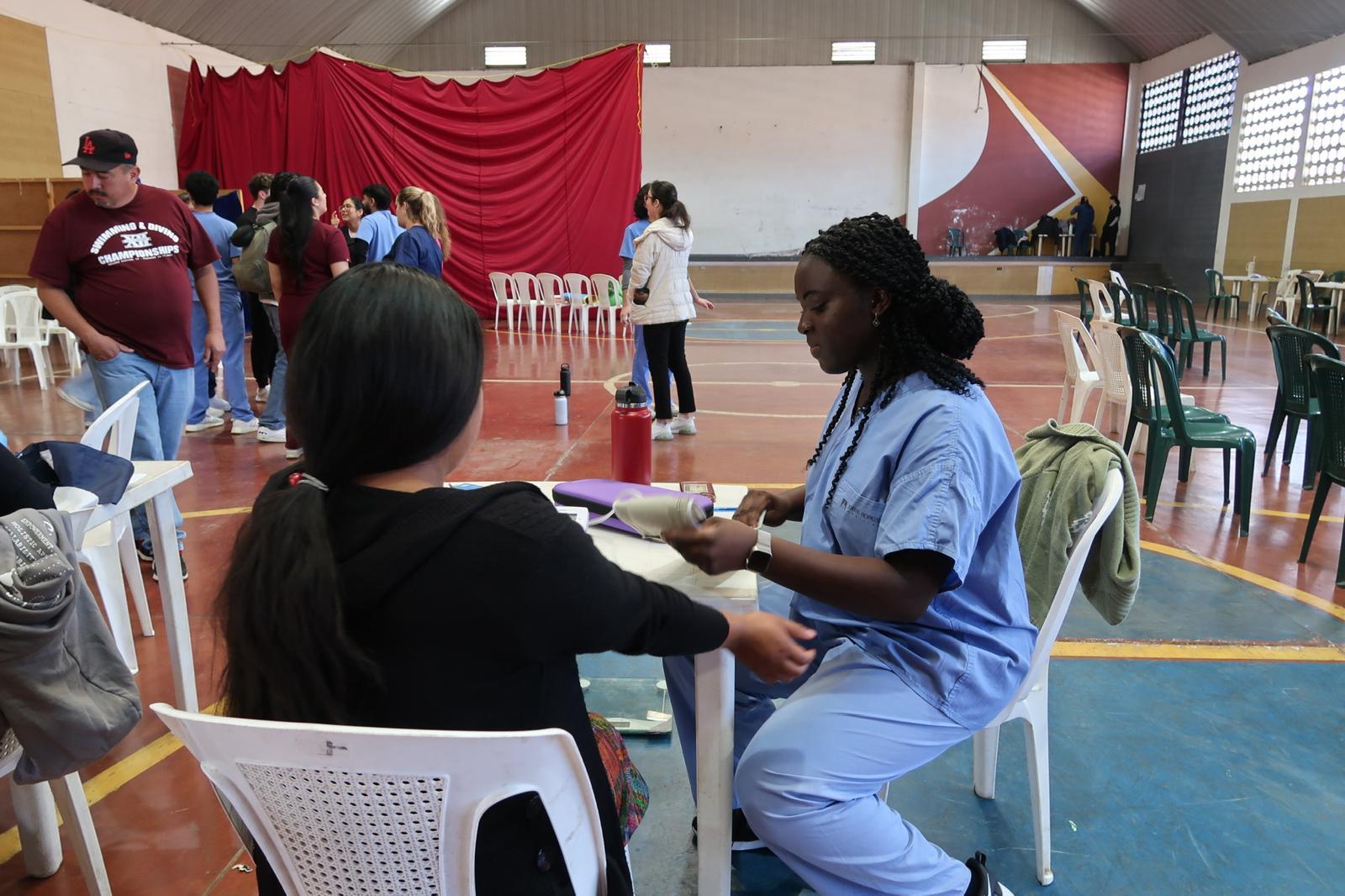 Gemstone student wearing medical gear taking blood pressure of a patient 