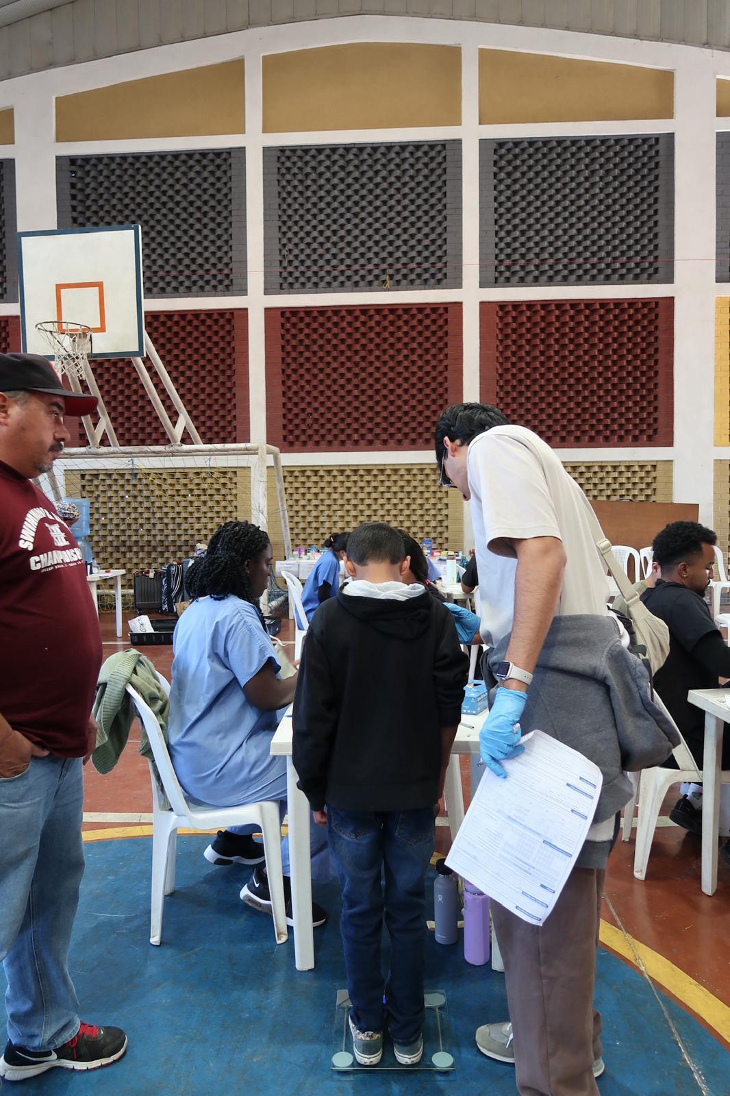 Photo of student wearing medical gear sitting at a table with other people