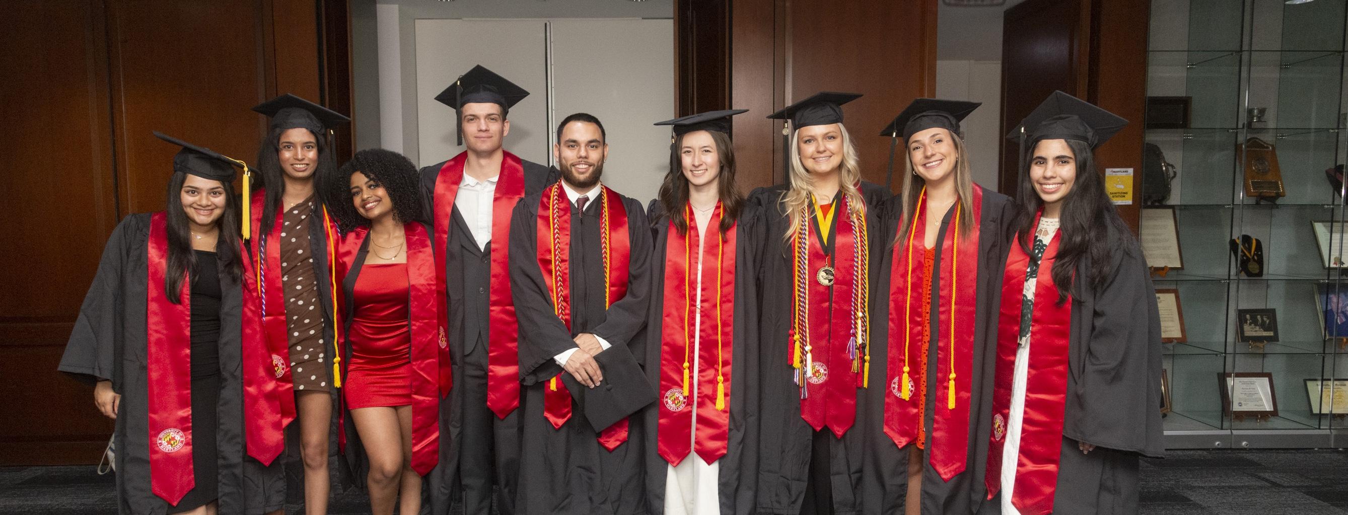 Group of graduating Gemstone students posing for photo in black and red gowns