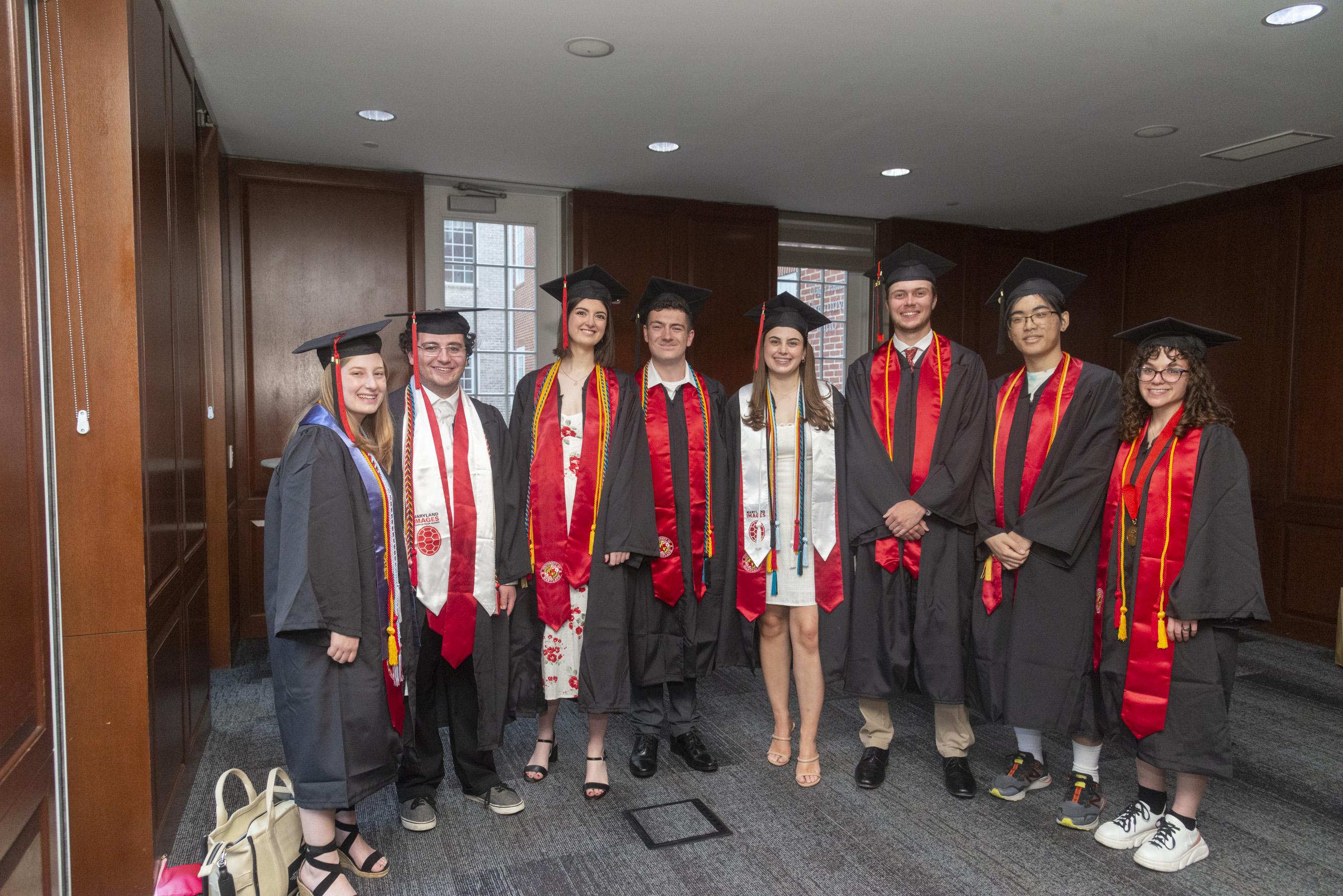 Group of graduating Gemstone students posing for photo in black and red gowns