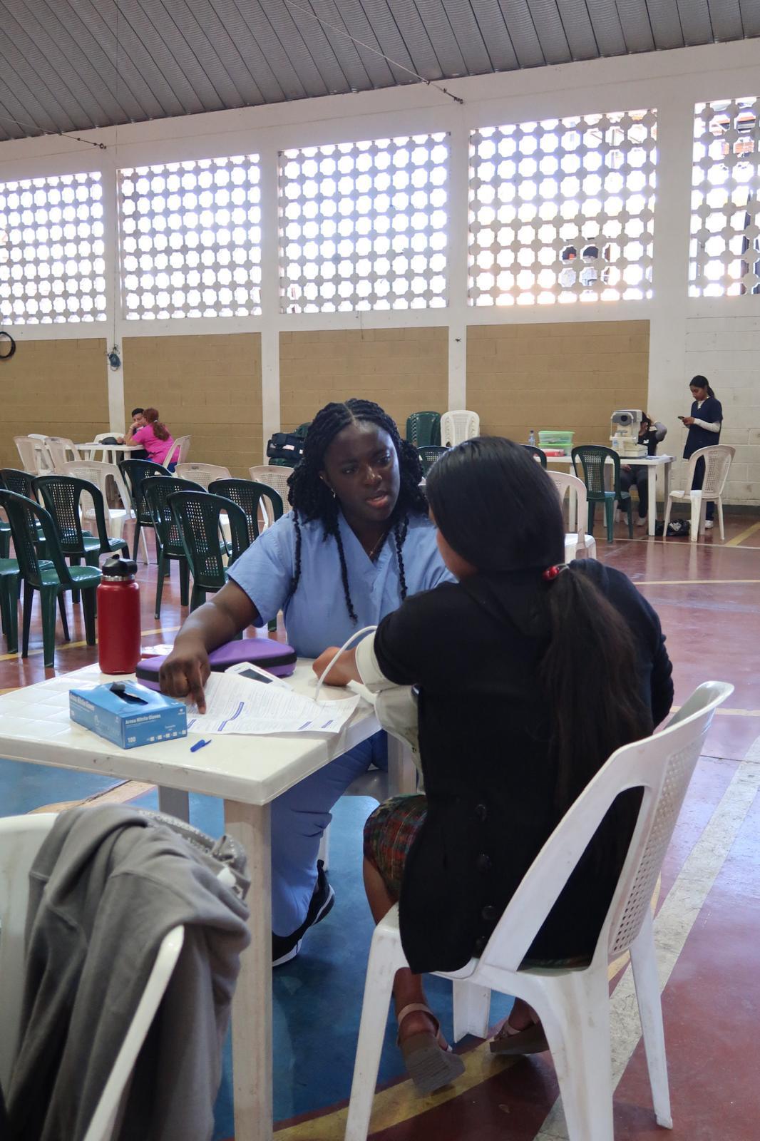 Gemstone student wearing medical gear taking blood pressure of a patient 