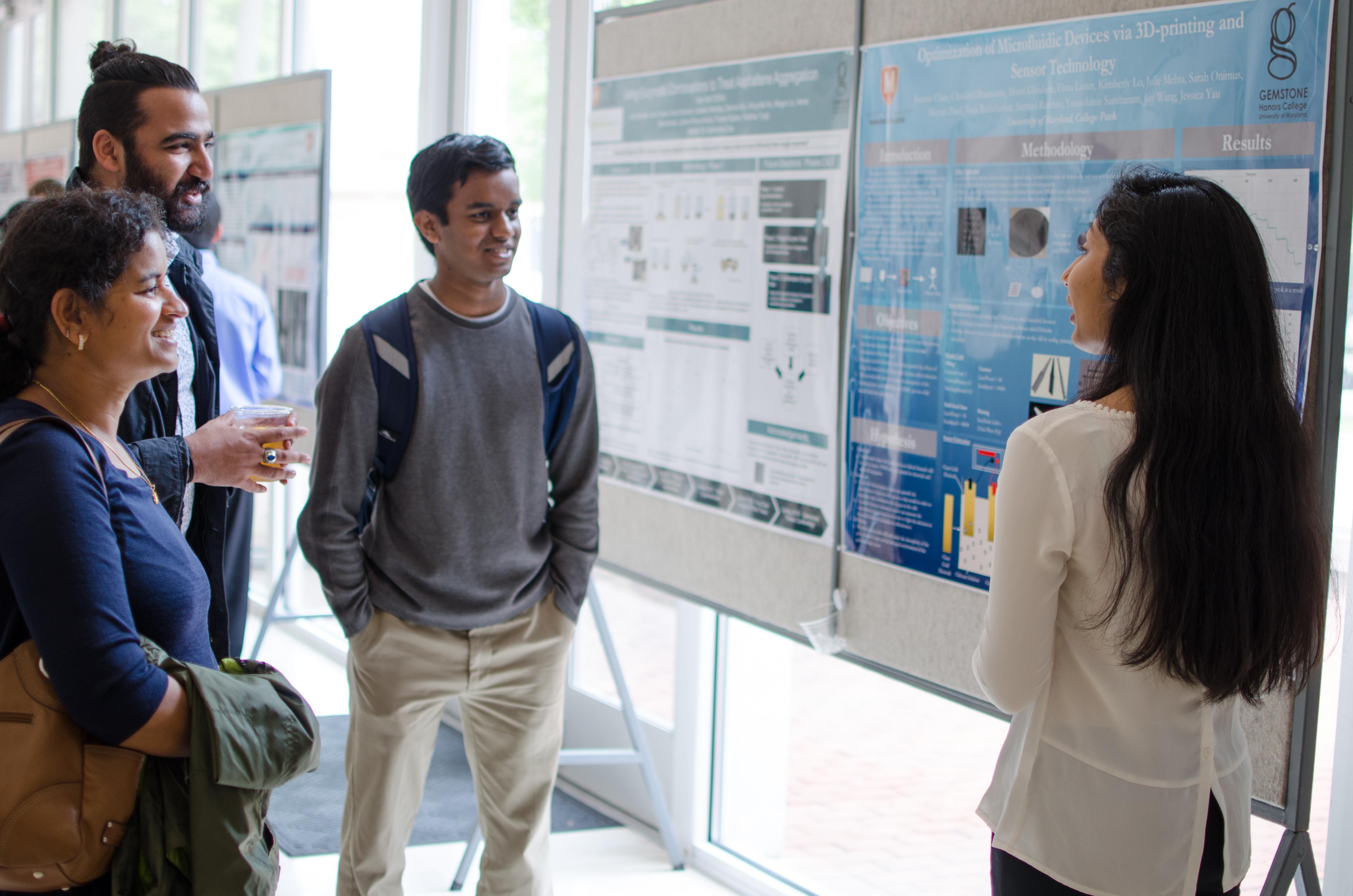 Students standing in front of poster presentation having a conversation