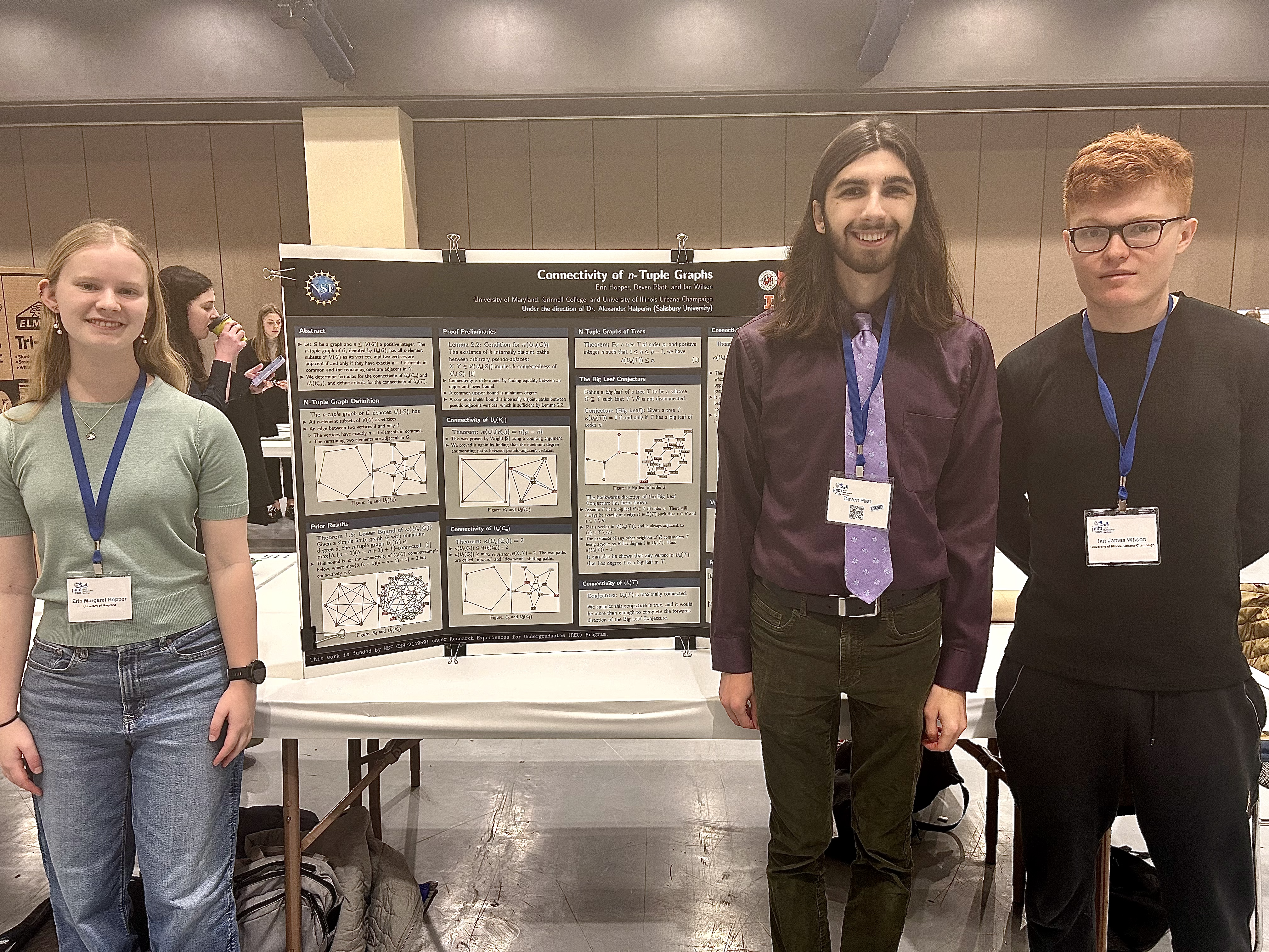 Three students standing next to poster board at a conference