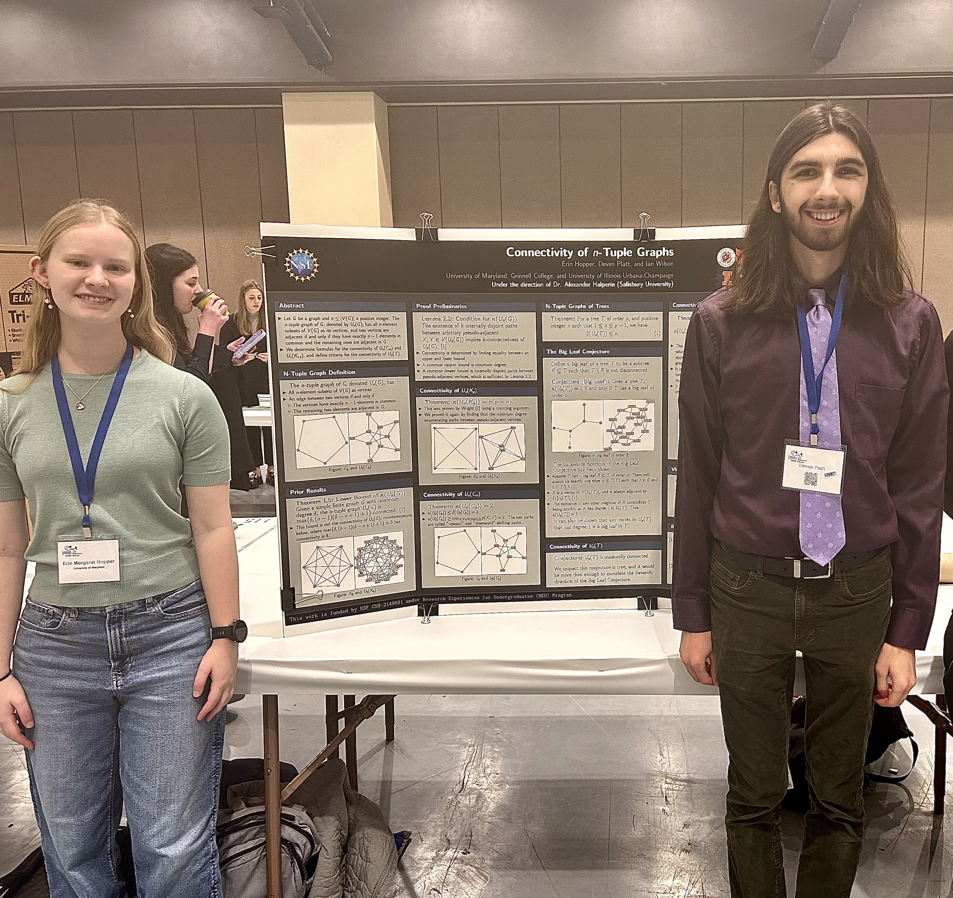 Two students standing next to poster board at a conference