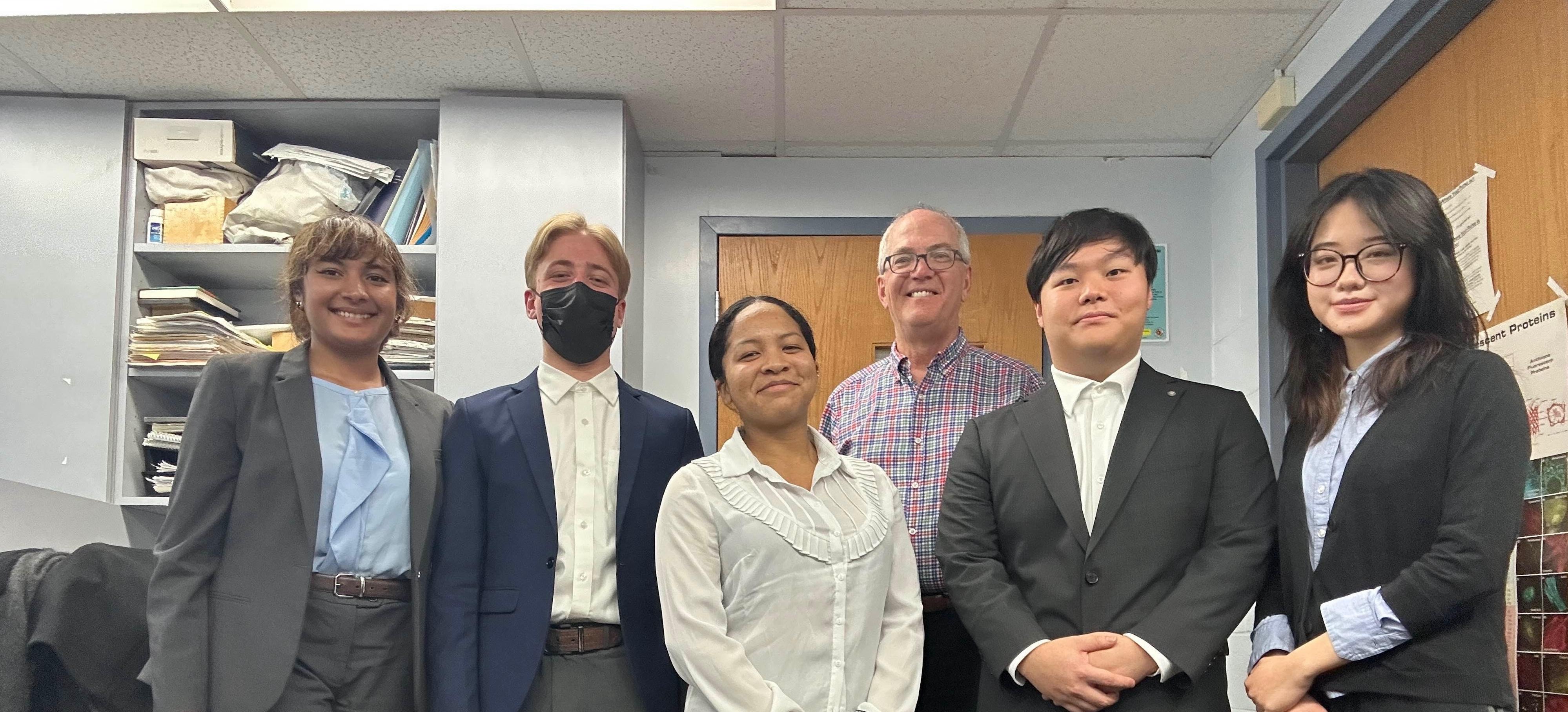 Five students and faculty mentor posing for a team photo inside an office