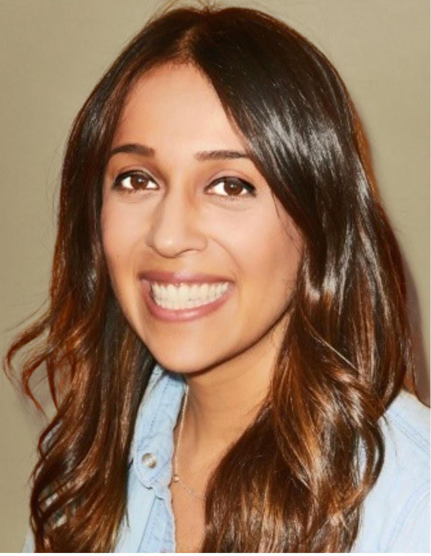 Photo of Devi Mahadevia in light blue shirt against tan background