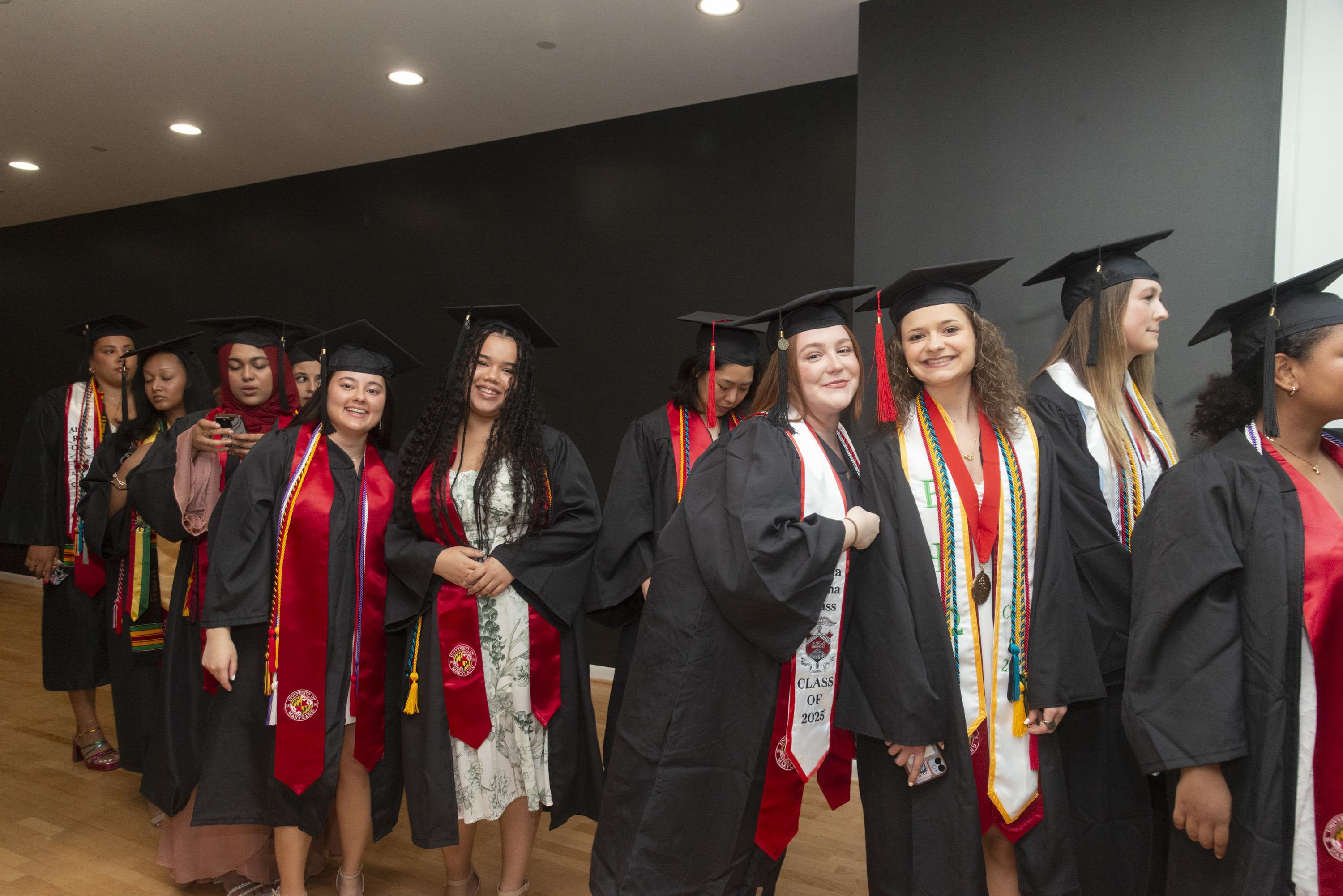 Gemstone students wearing graduation caps and gowns standing in line