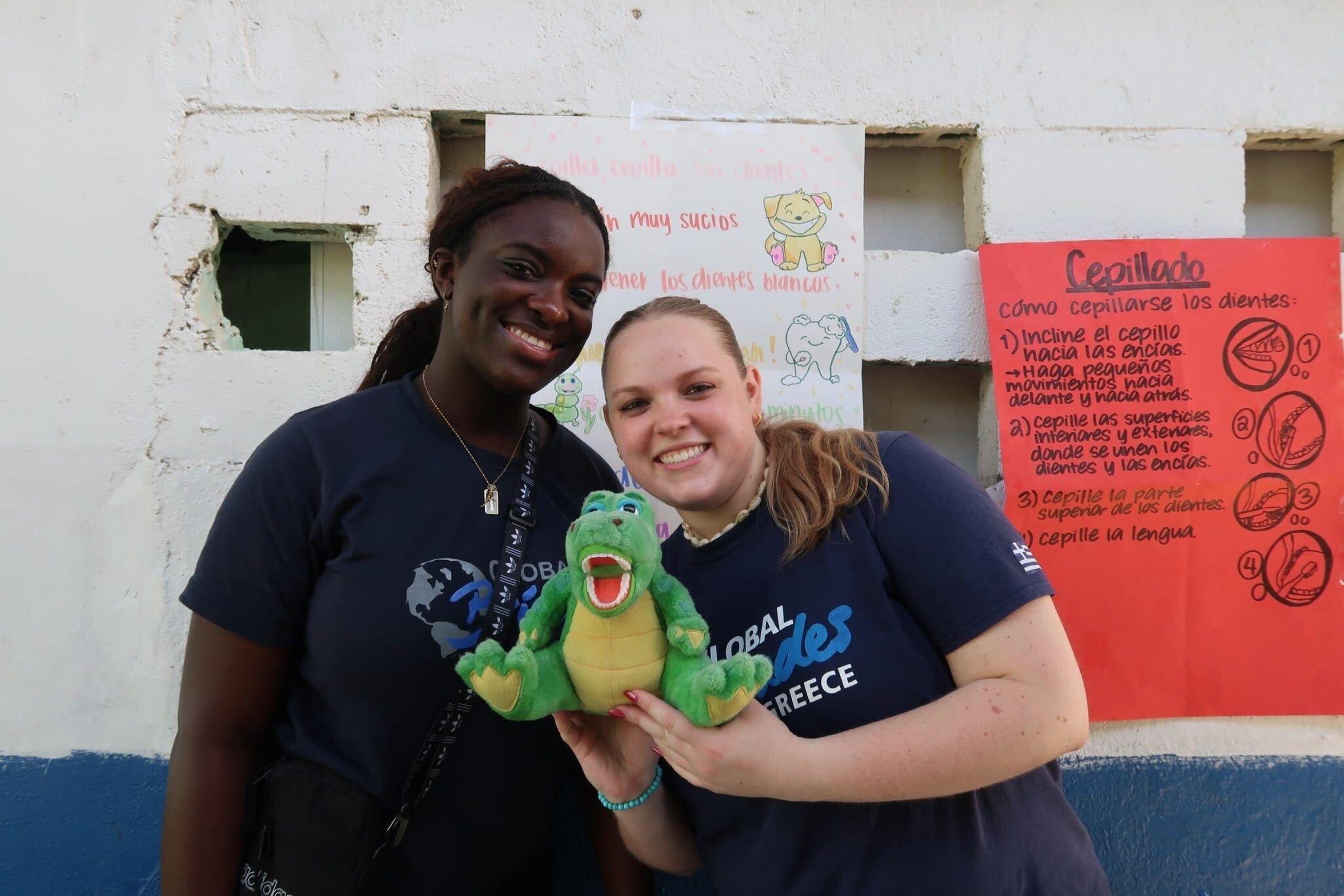 Tami Mumuney and another student smiling and holding a stuffed animal dinosaur