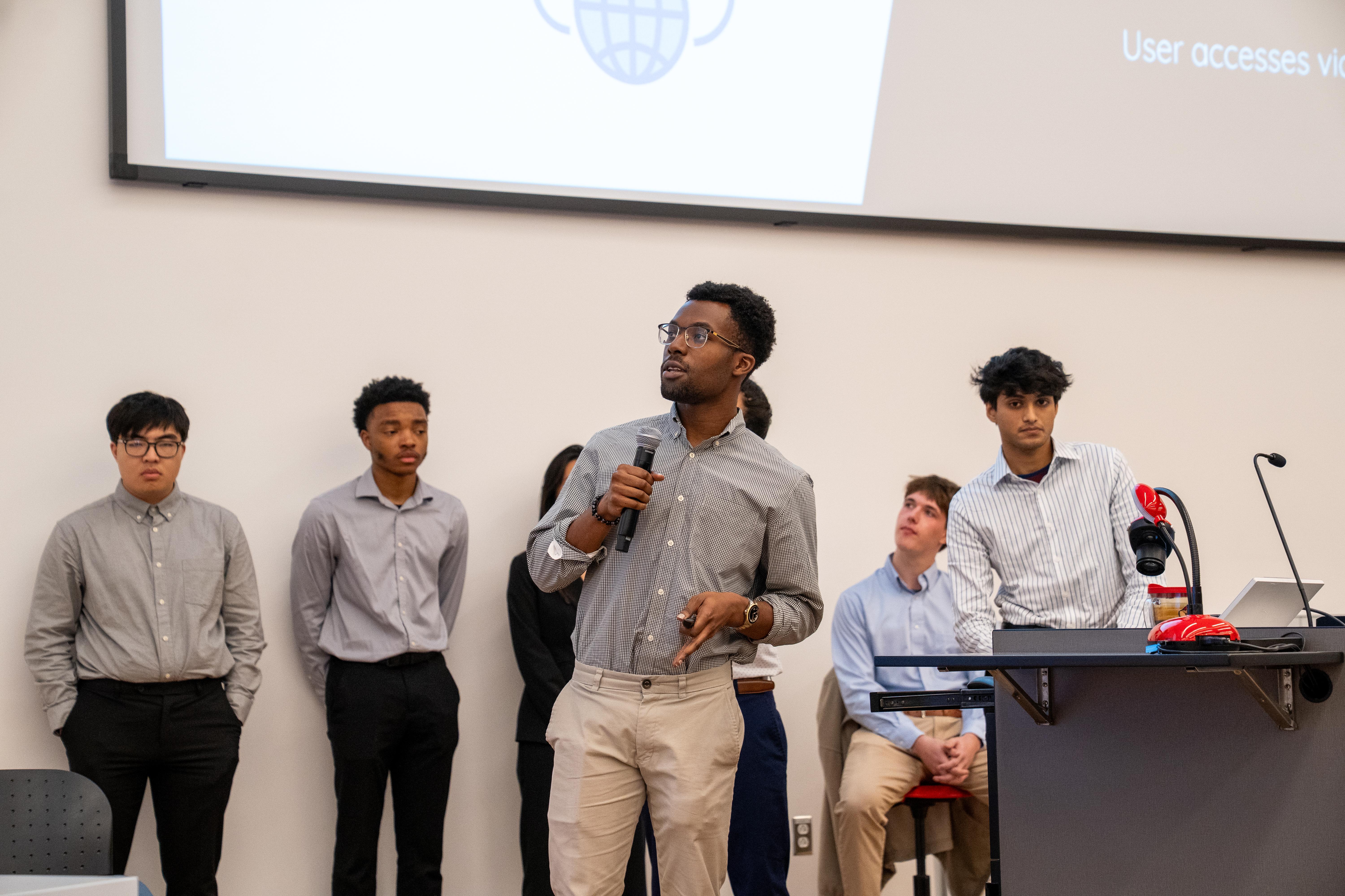 Gemstone student holding microphone with teammates in the background