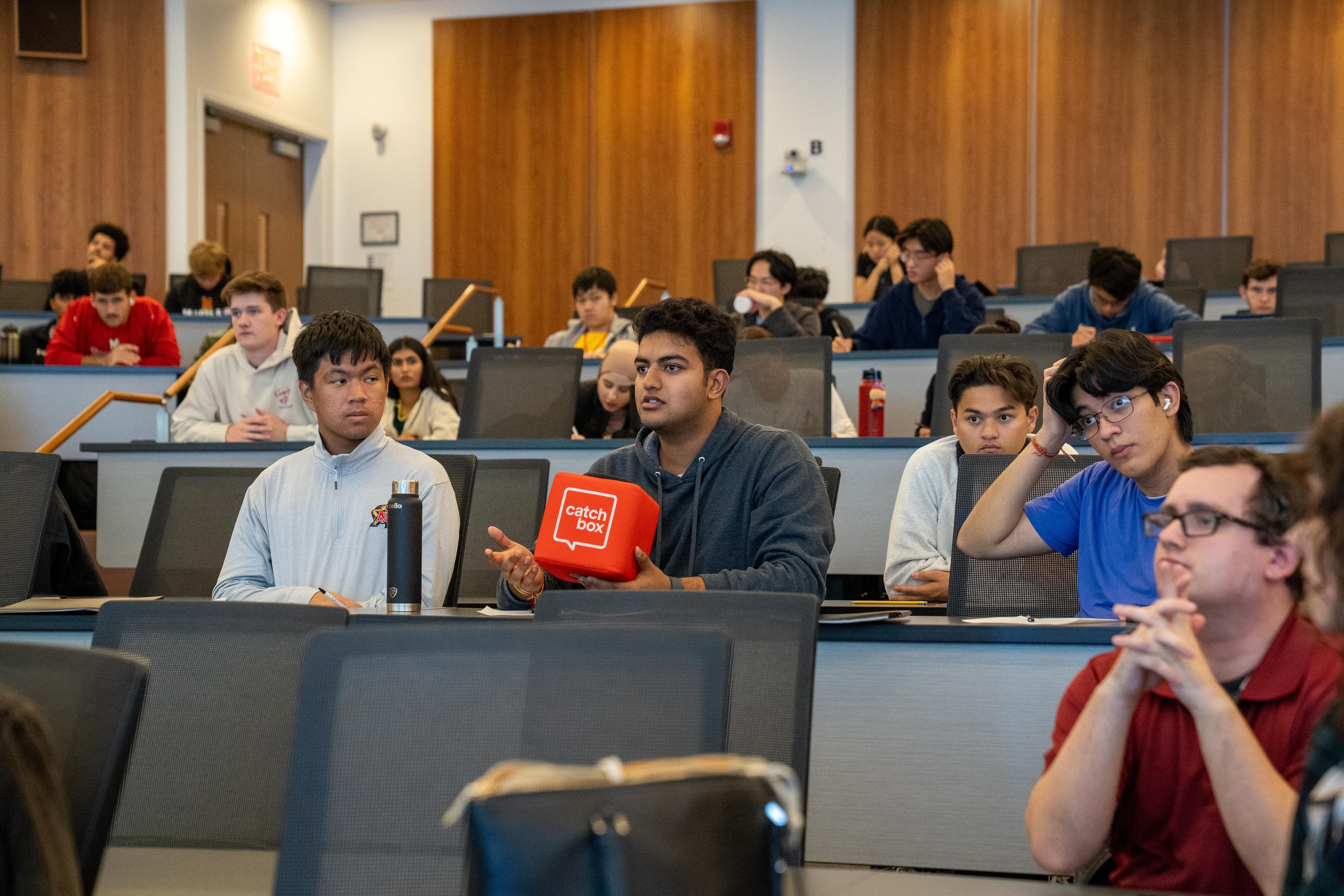 Gemstone student holding catchbox microphone seated in a lecture hall