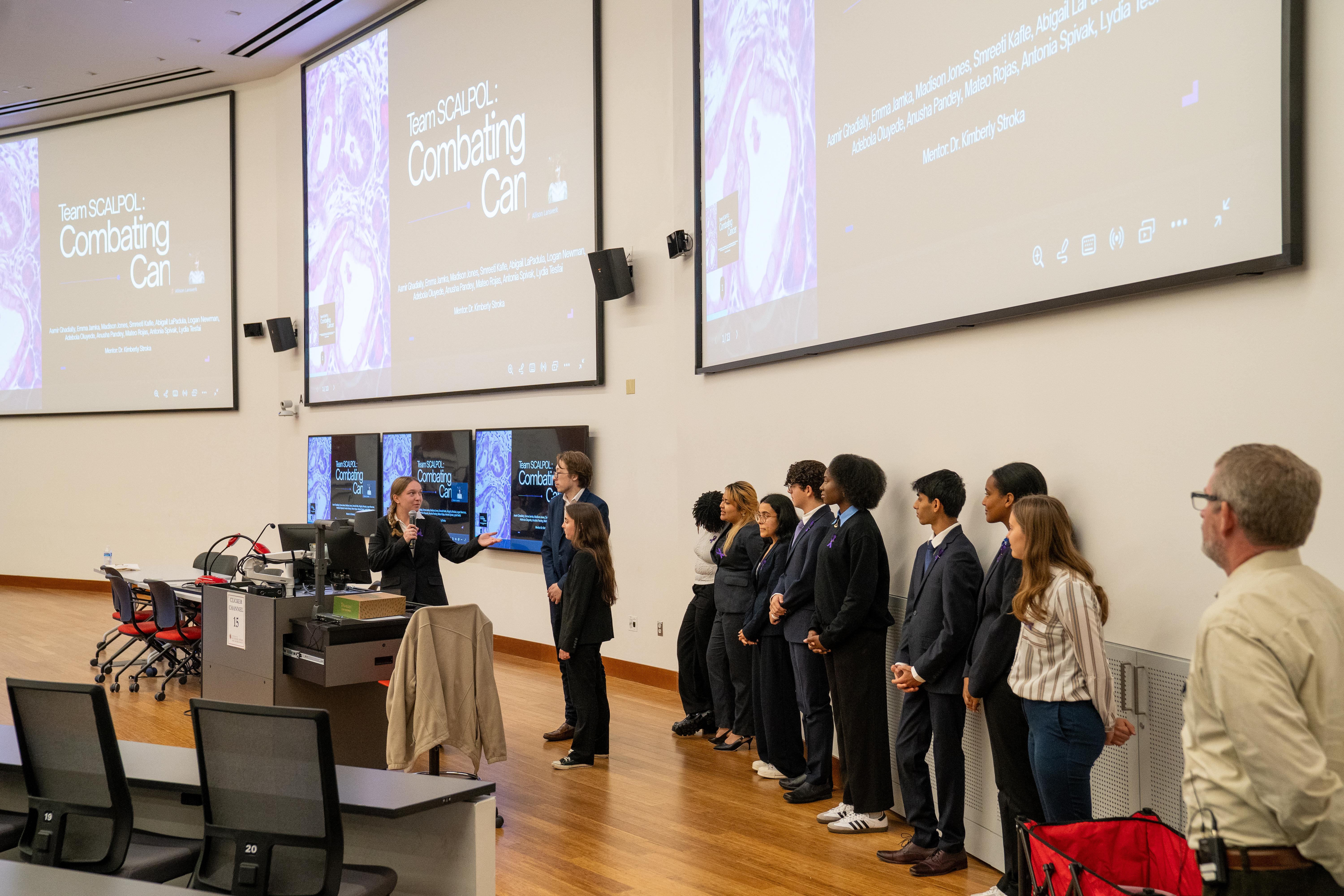 Gemstone student holding microphone with teammates in the background
