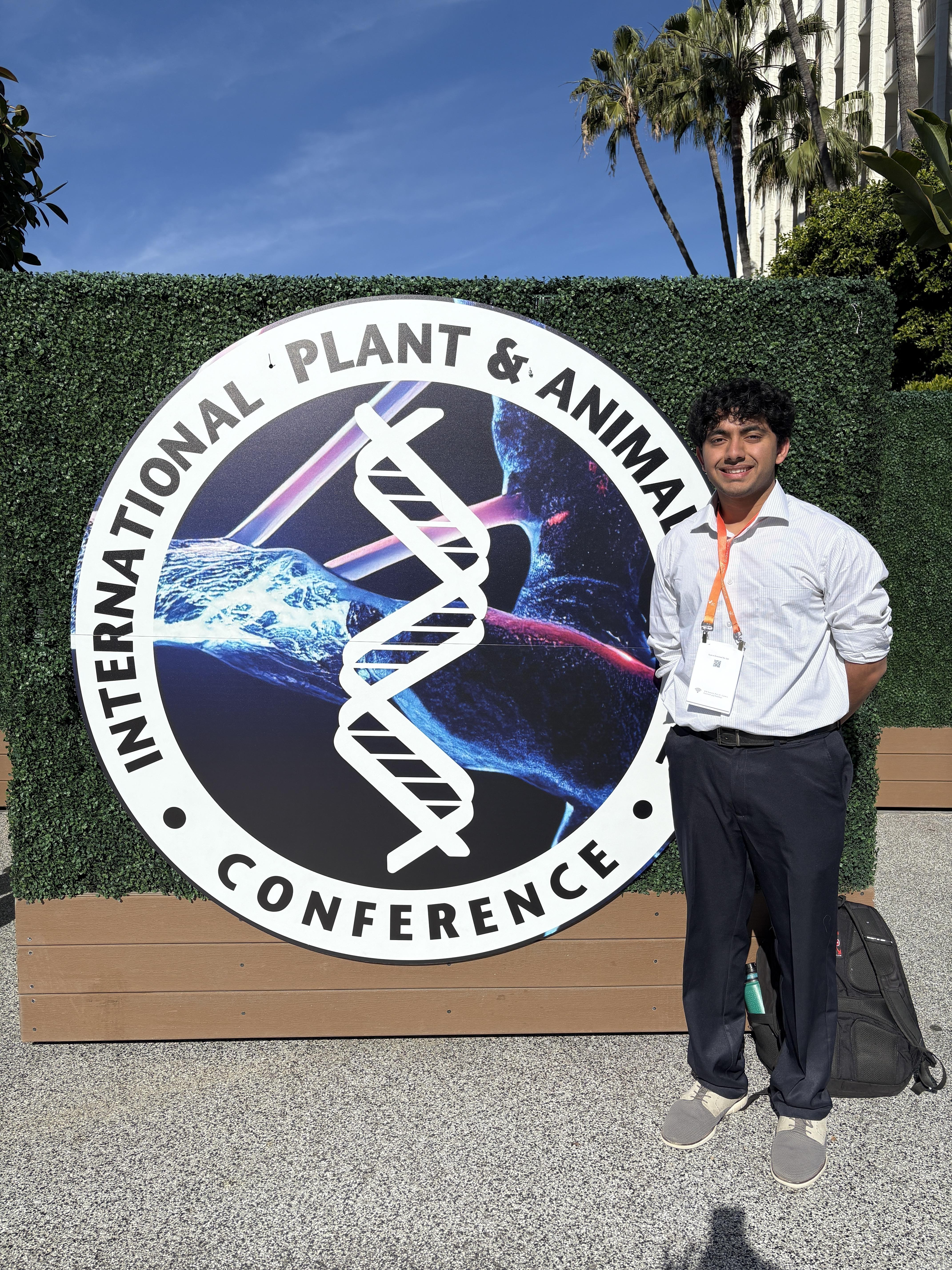Photo of Bhargav standing in front of sign for International Plant and Animal Genome conference